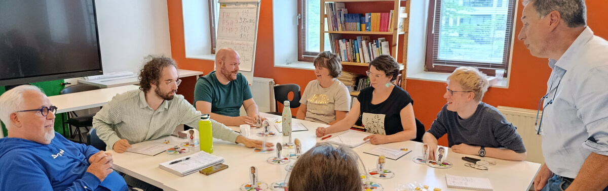 Atelier de sensibilisation : sept personnes autour d'une table manipulent figurines et fiches pédagogiques.