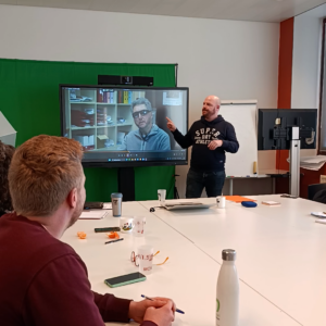 Image de notre formateur en langue des signes donne court dans une salle avec une télévision en support visuel pour ses explications